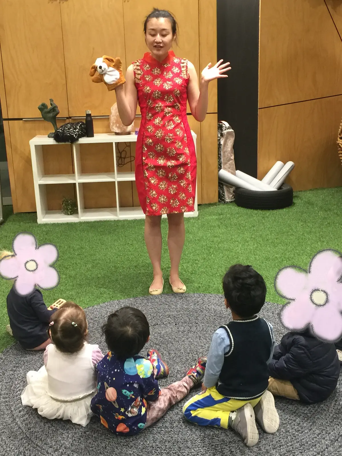 Raina holding a puppet while toddlers watch