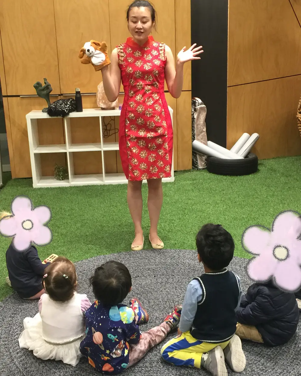 Raina holding a puppet while toddlers watch