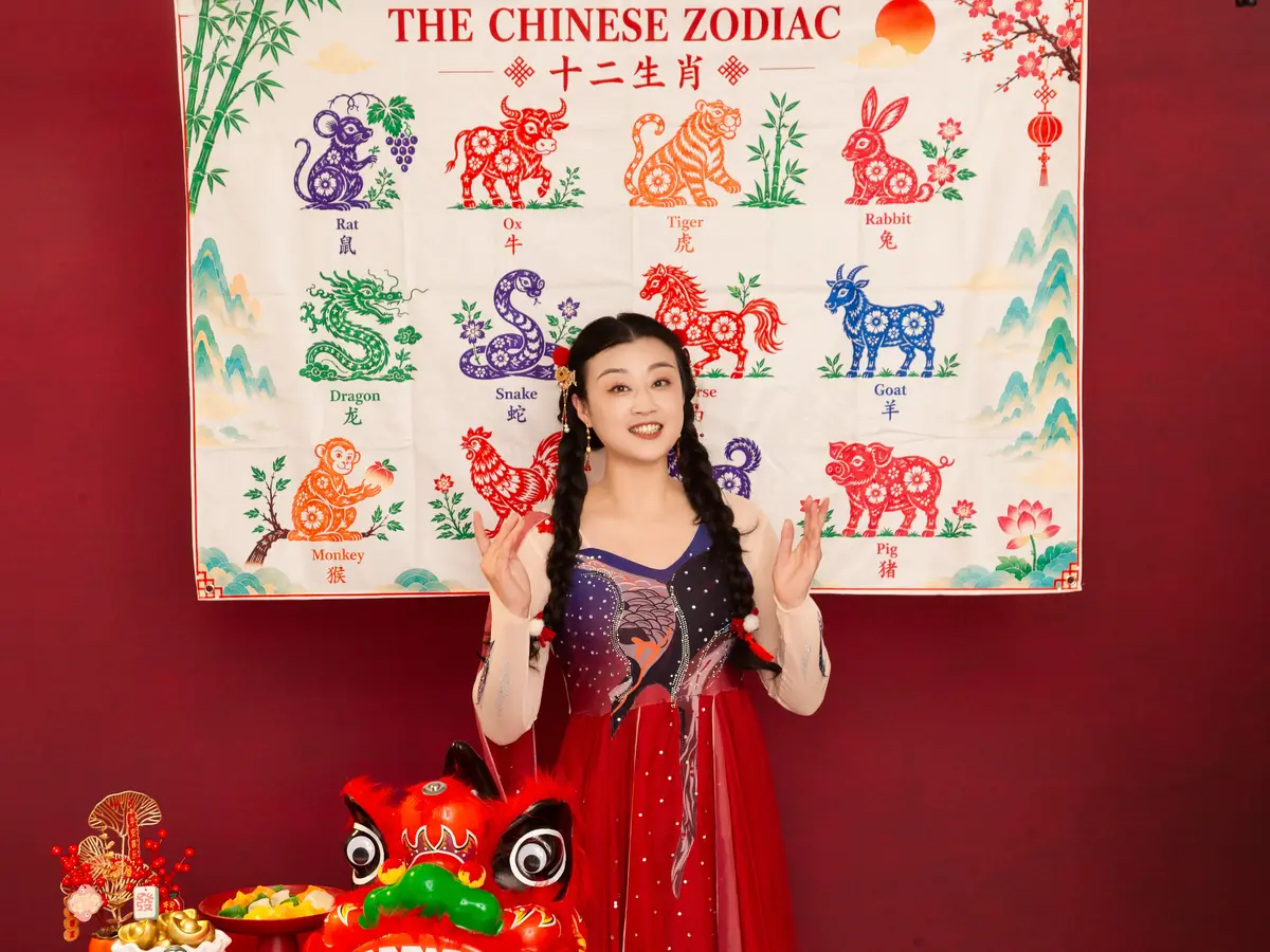Raina waving in front of a Chinese zodiac backdrop