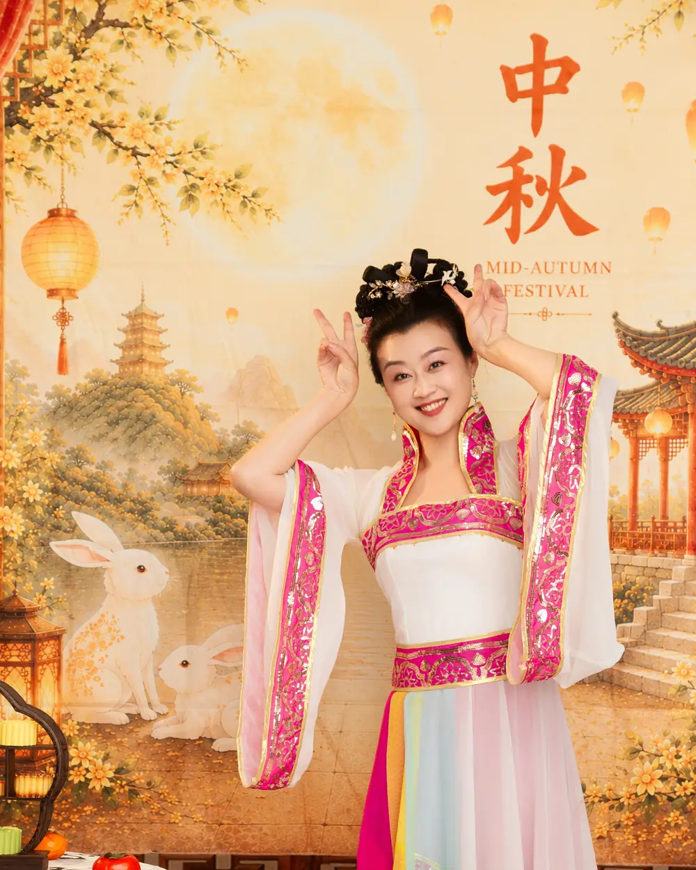 Raina in a Mid-Autumn costume in front of a backdrop with a rabbit, lanterns and a pagoda