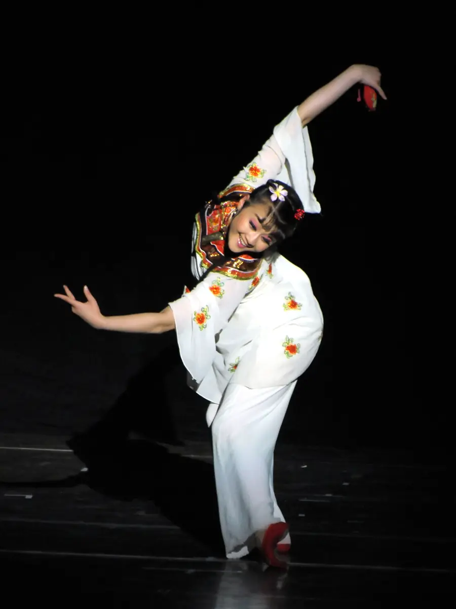 Raina performing a Chinese dance on stage in a white costume