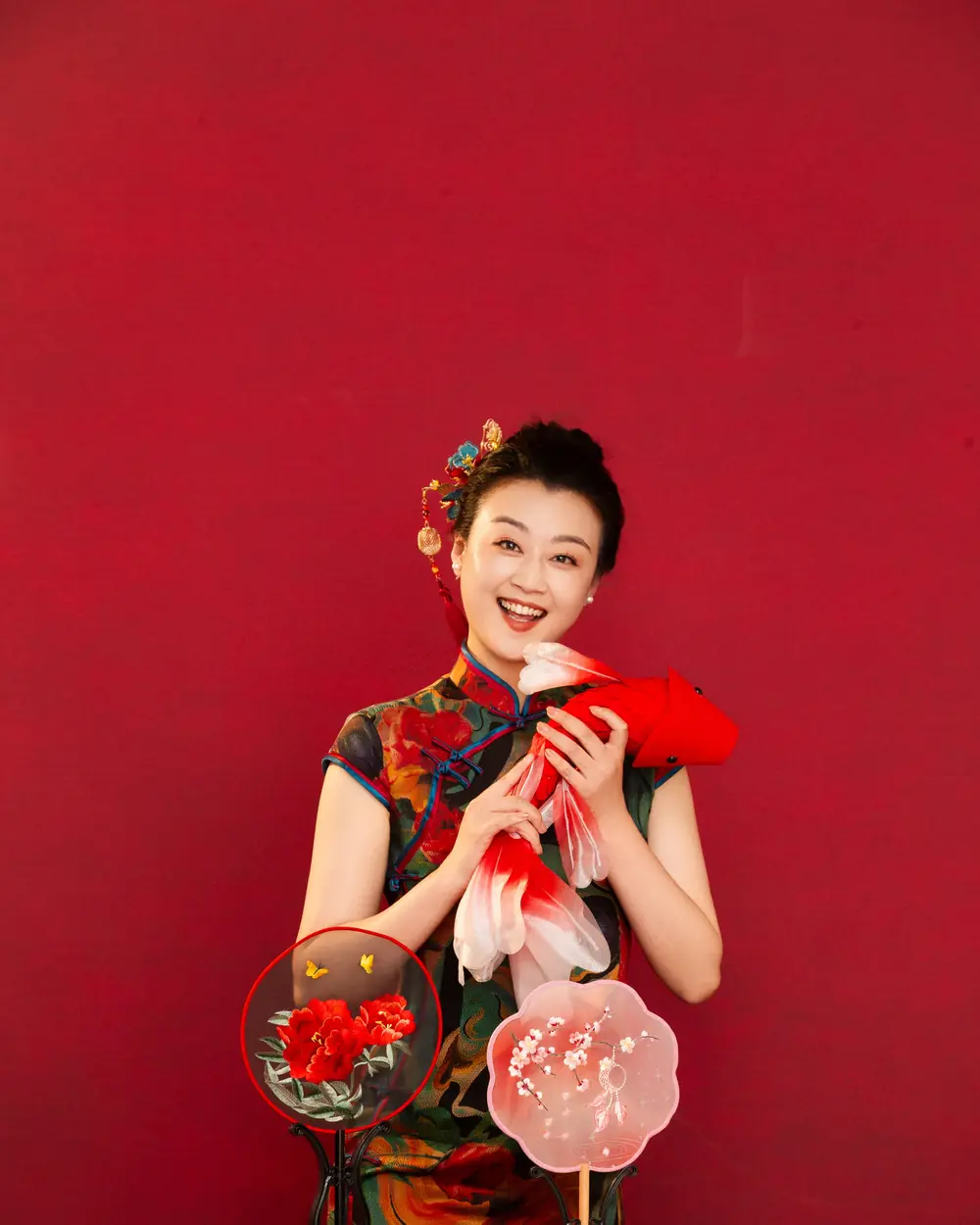 Raina in a floral qipao holding traditional props